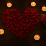 Red rose petals in a heart shape among candles, love ritual